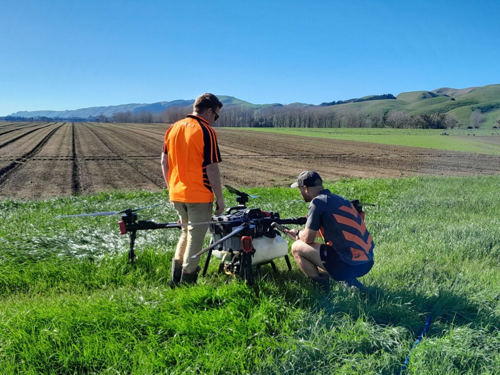 Two operators carrying out a pre-flight check on a spray drone in the field